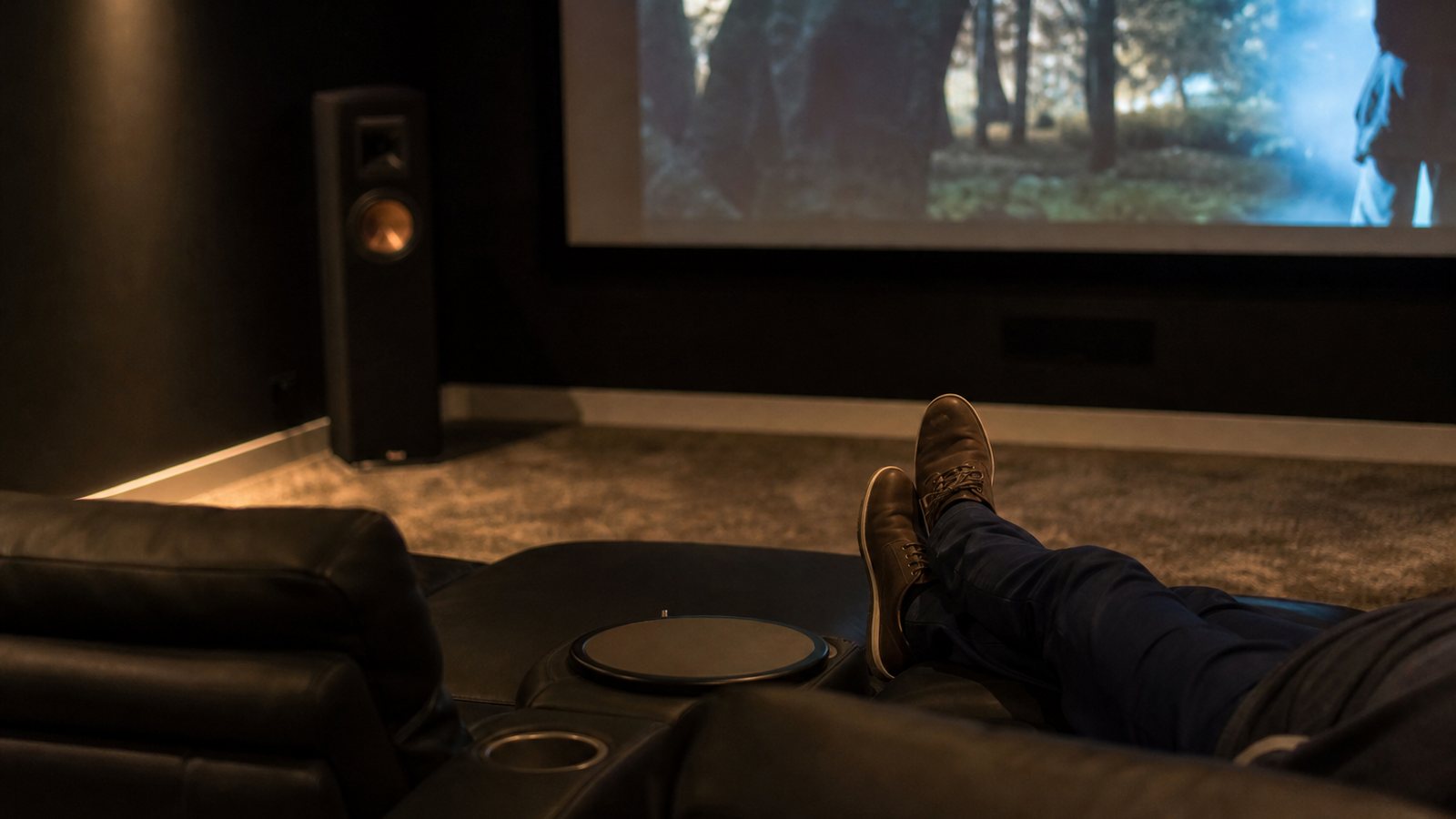 Fauteuils inclinables alignés en deux rangées face au grand écran d'une salle de cinéma privée
